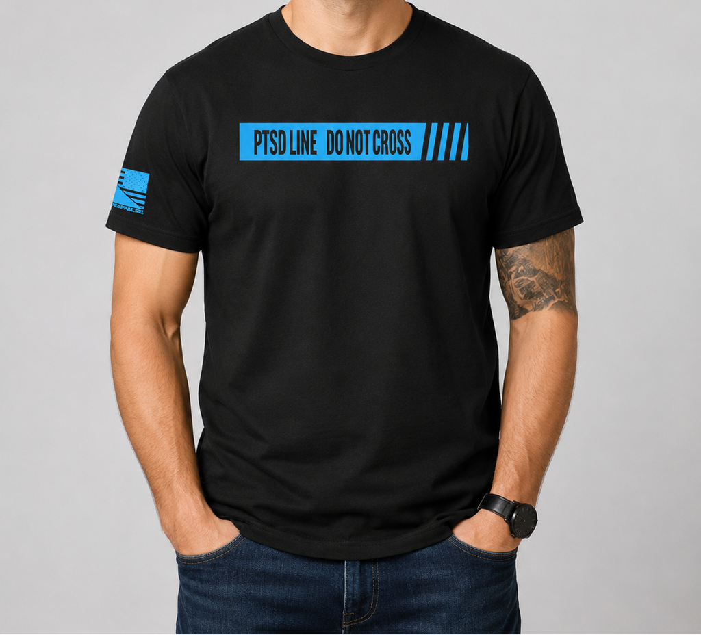 A man wearing a black crewneck t-shirt with a blue 'PTSOLINE DO NOT CROSS' graphic on the chest and a blue flag design on the sleeve, set against a plain gray studio background.