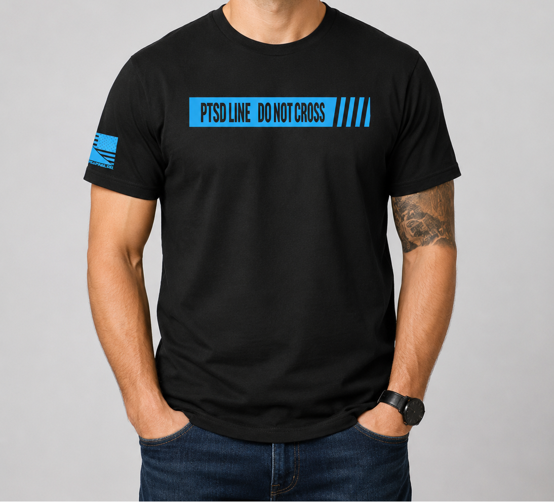 A man wearing a black crewneck t-shirt with a blue 'PTSOLINE DO NOT CROSS' graphic on the chest and a blue flag design on the sleeve, set against a plain gray studio background.